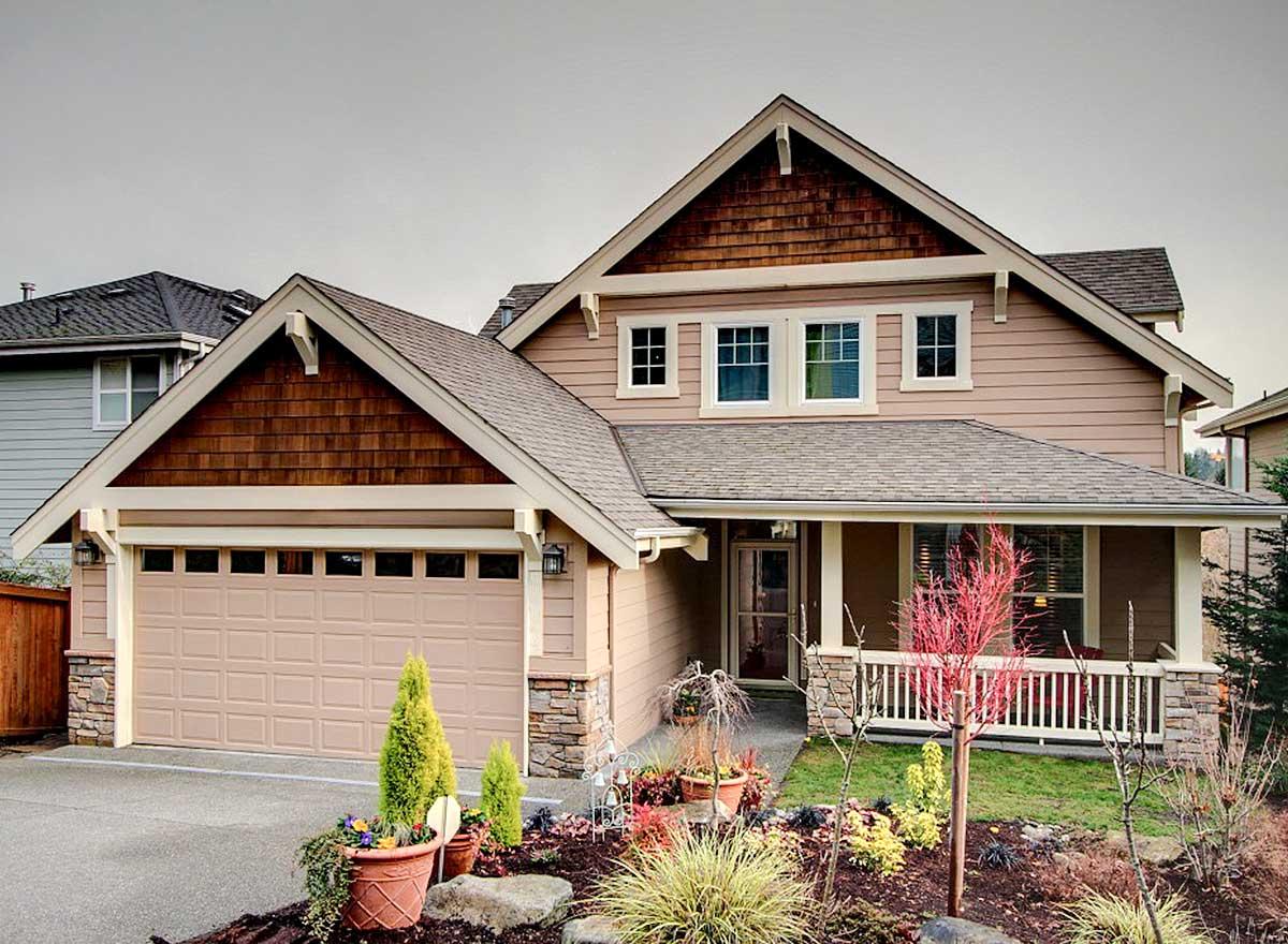 House plan exterior. Two-story Craftsman home with a gabled roof, shake siding, a covered porch, and a two-car garage.