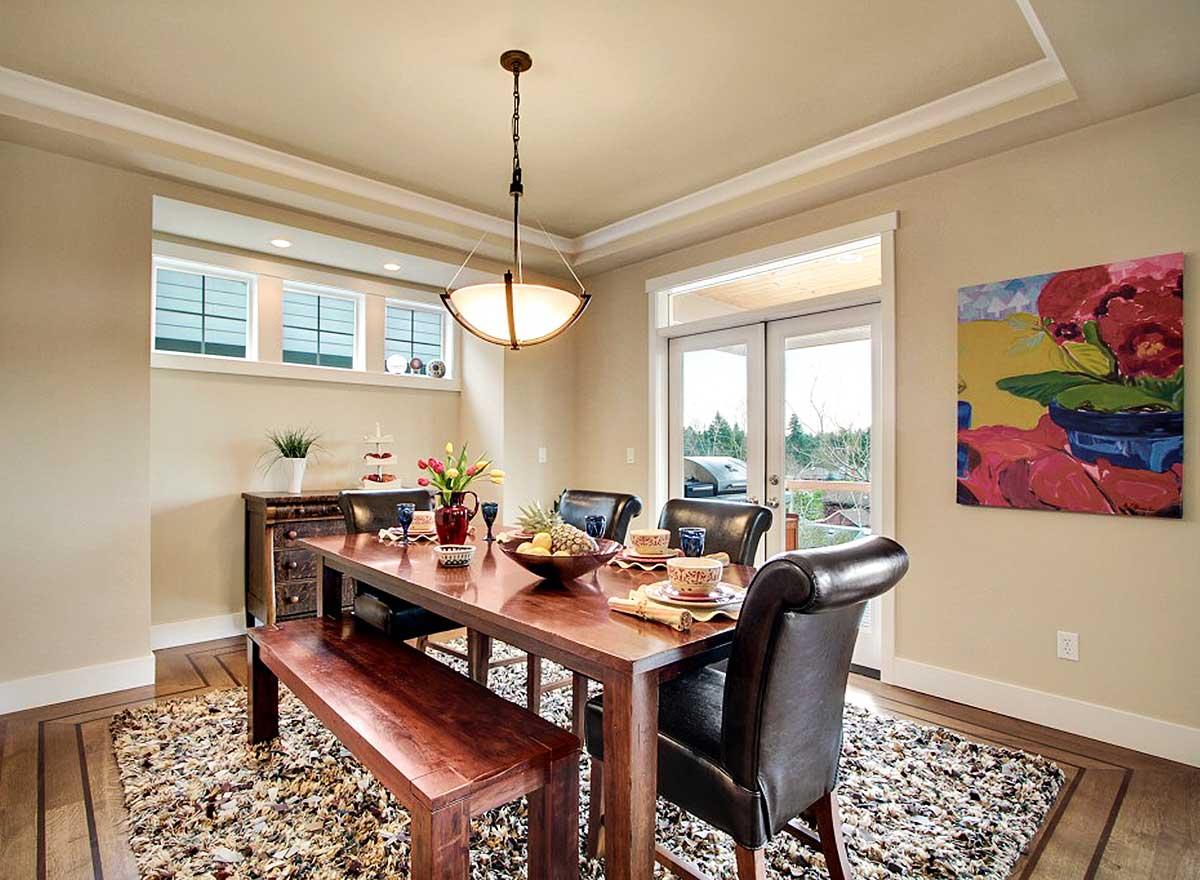 Dining room with wooden table, chairs, bench, pendant light, and French doors leading to an outdoor deck.