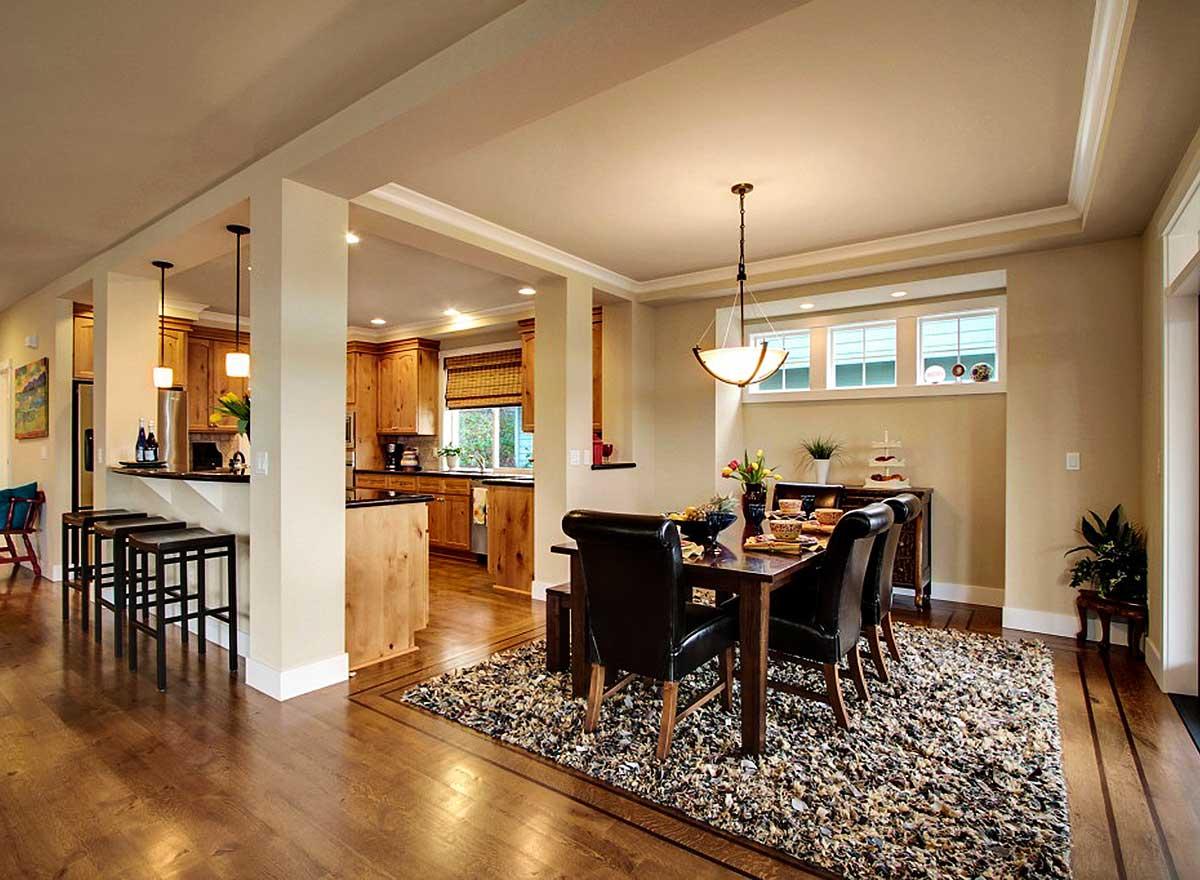 Open concept interior with dining area, kitchen island, breakfast bar with pendant lights, and wood cabinetry.