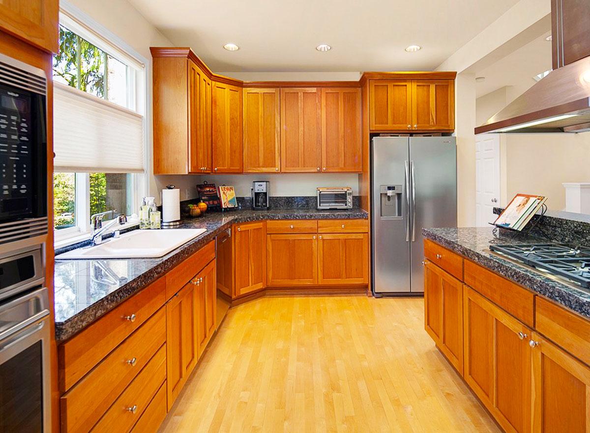 Kitchen with light wood cabinets, granite countertops, stainless steel appliances including a refrigerator and double oven, and a large window.