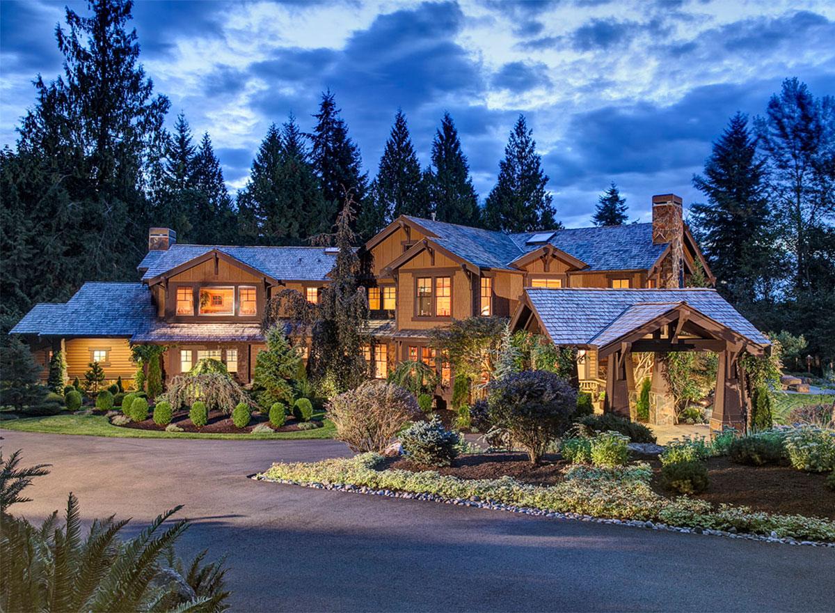 House plan exterior view of a multi-story lodge-style home with stone chimney, gables, and a covered porte-cochère.