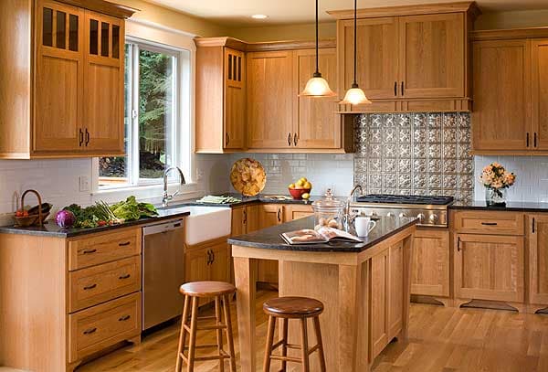 Kitchen with natural wood cabinets, a white apron sink, stainless steel range, and a central island with seating.