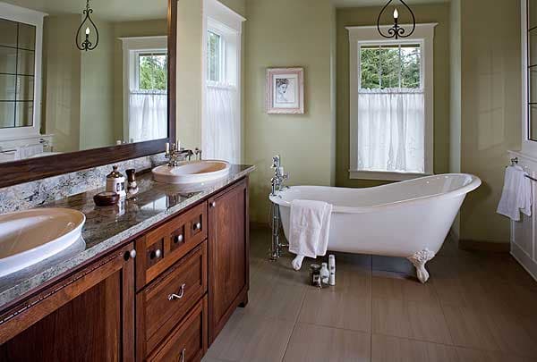 Bathroom interior with double vanity, freestanding tub, and two windows.