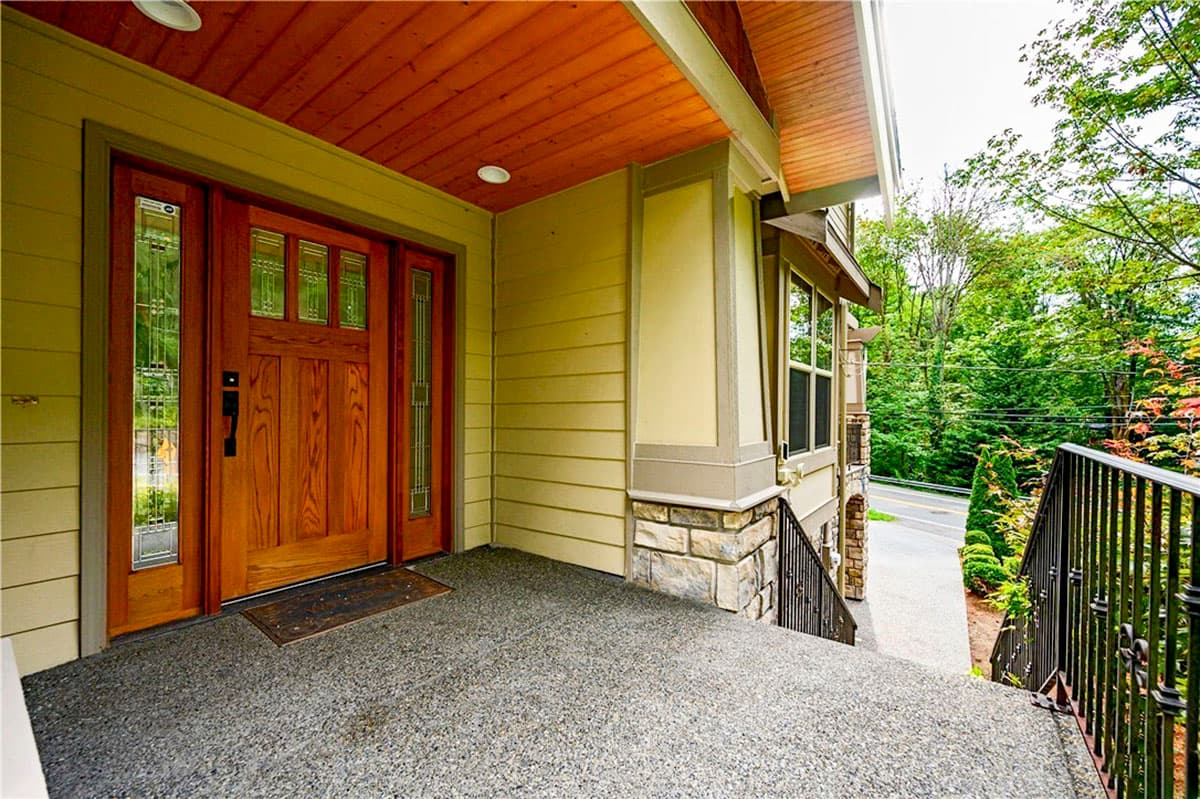 House plan exterior: wood-paneled ceiling on covered porch, craftsman-style double entry door with sidelights, and stone and siding facade.
