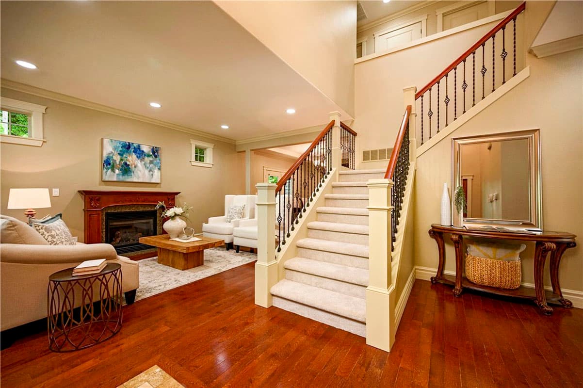 Interior view of a living room with a fireplace, staircase, and plush seating.
