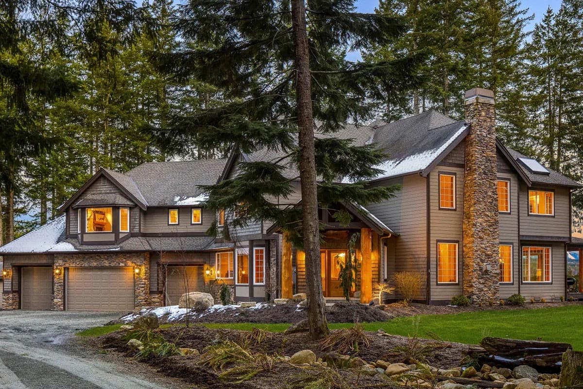 House plan exterior with stone chimney, multiple gables, three-car garage, and covered entry.