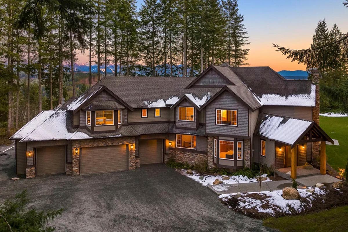 House plan exterior: multi-story home with intersecting rooflines, bay windows, stone accents, and a three-car garage.