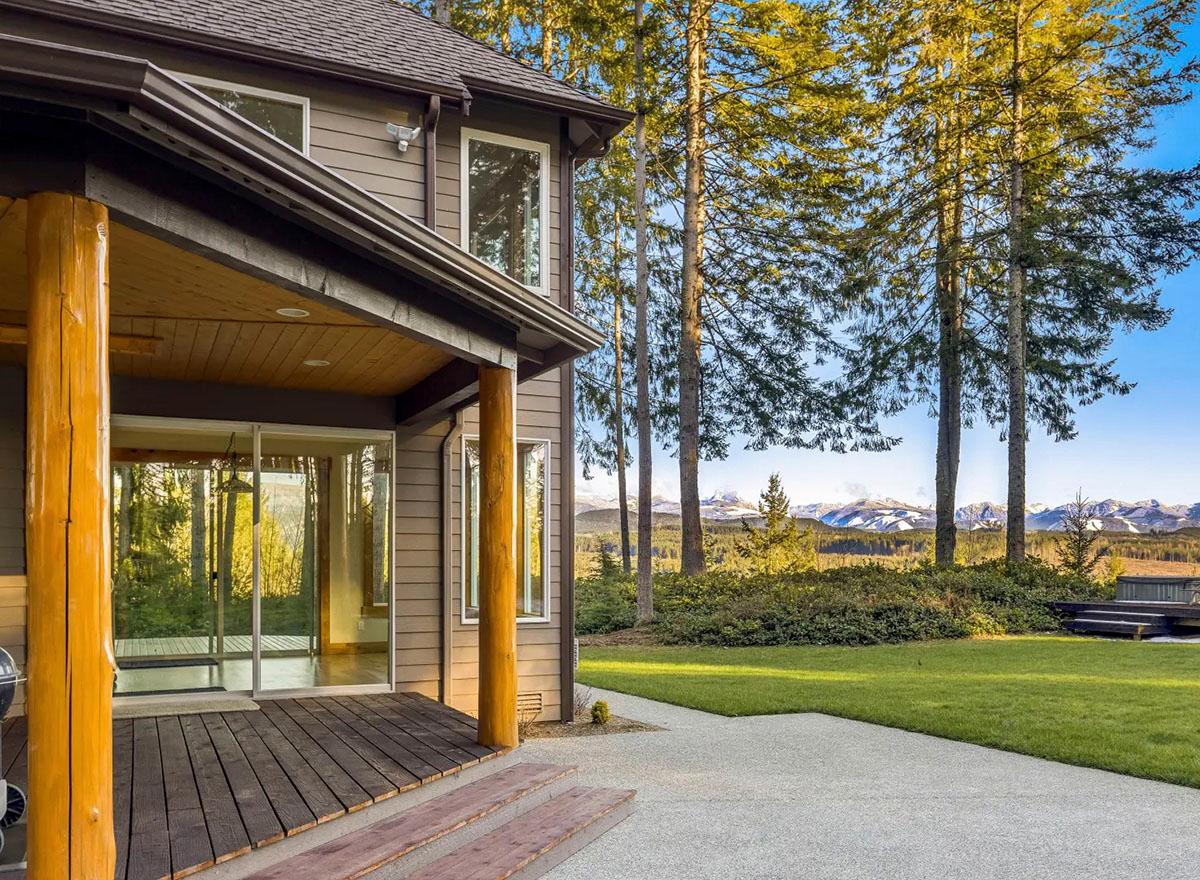 House plan exterior with covered porch, log posts, horizontal siding, and mountain views.