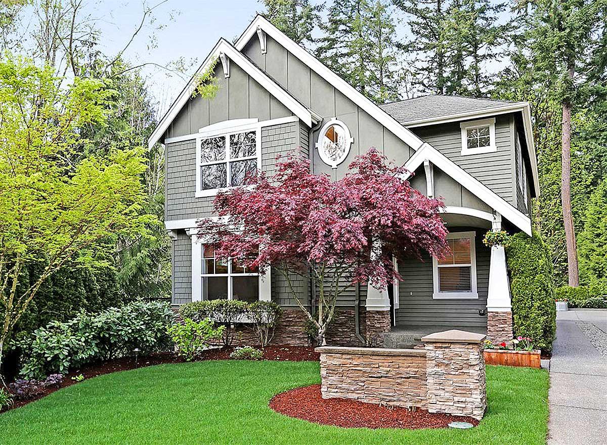 House plan exterior with two stories, prominent gables, shingle siding, and a covered porch with stone accents.
