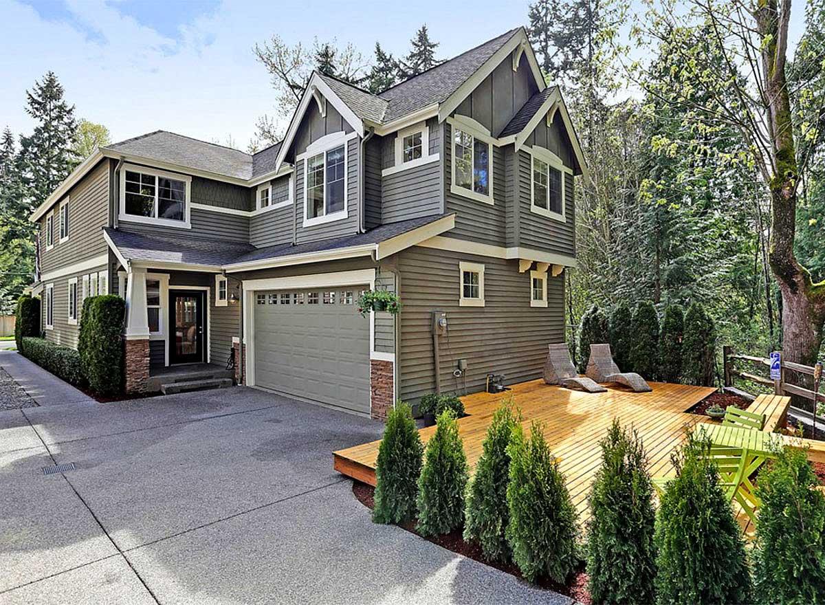 Two-story house plan exterior with gabled dormers, covered entry, attached garage, and a wooden deck.