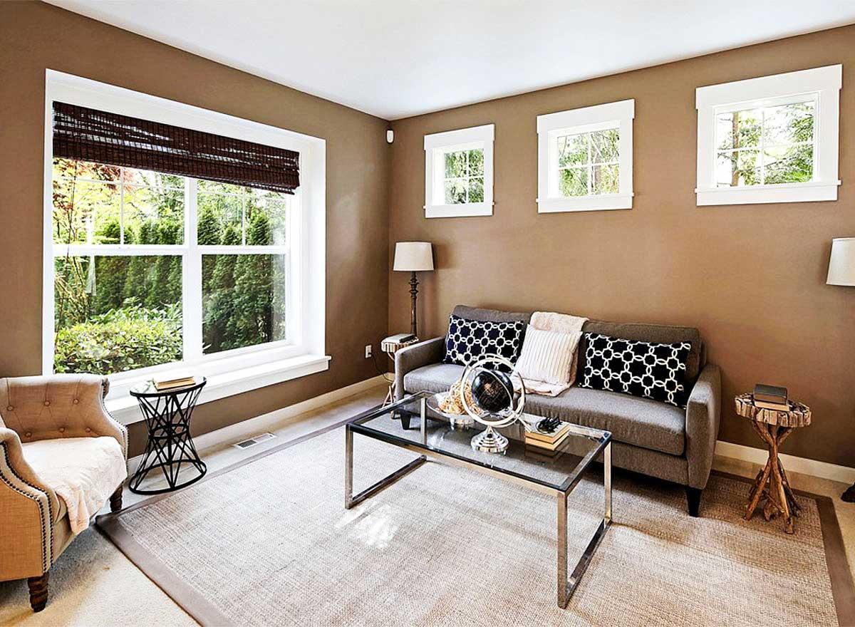 Living room with large bay window, sofa, accent chairs, and glass coffee table. Elevated view.