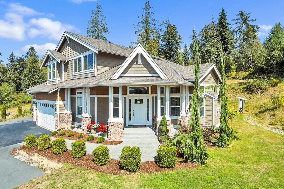 House plan exterior with stone accents, covered entry with columns, multiple gables, and a two-car garage.