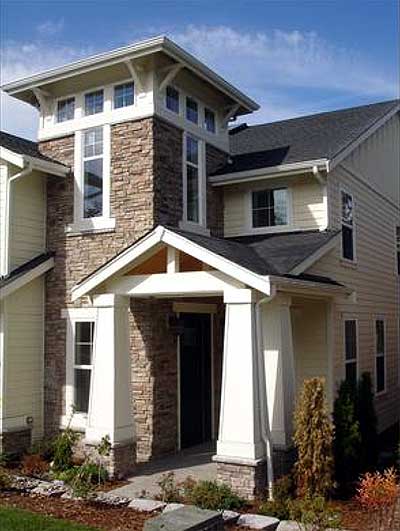 House plan exterior with stone accents, covered entry with columns, and prominent gabled dormers.