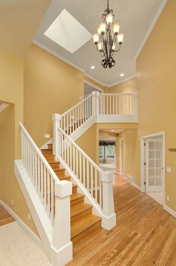 Two-story foyer with a wood staircase, white balustrades, and a skylight above.