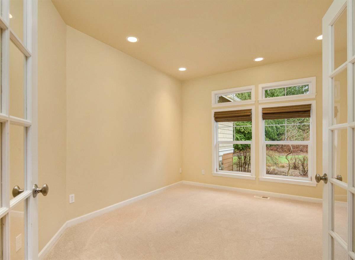 Interior view of an office with French doors, carpet, recessed lighting, and a double window with exterior view.