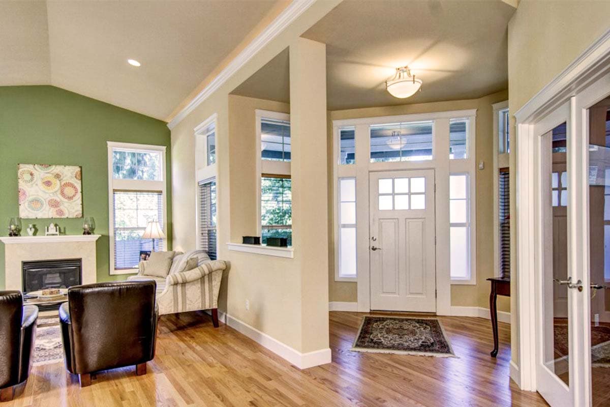 Interior view of entryway with fireplace, vaulted ceiling, and front door with sidelights.