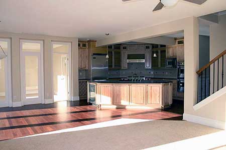 Open concept living area featuring a large kitchen with island, stainless steel appliances, and view of stairs and double doors.