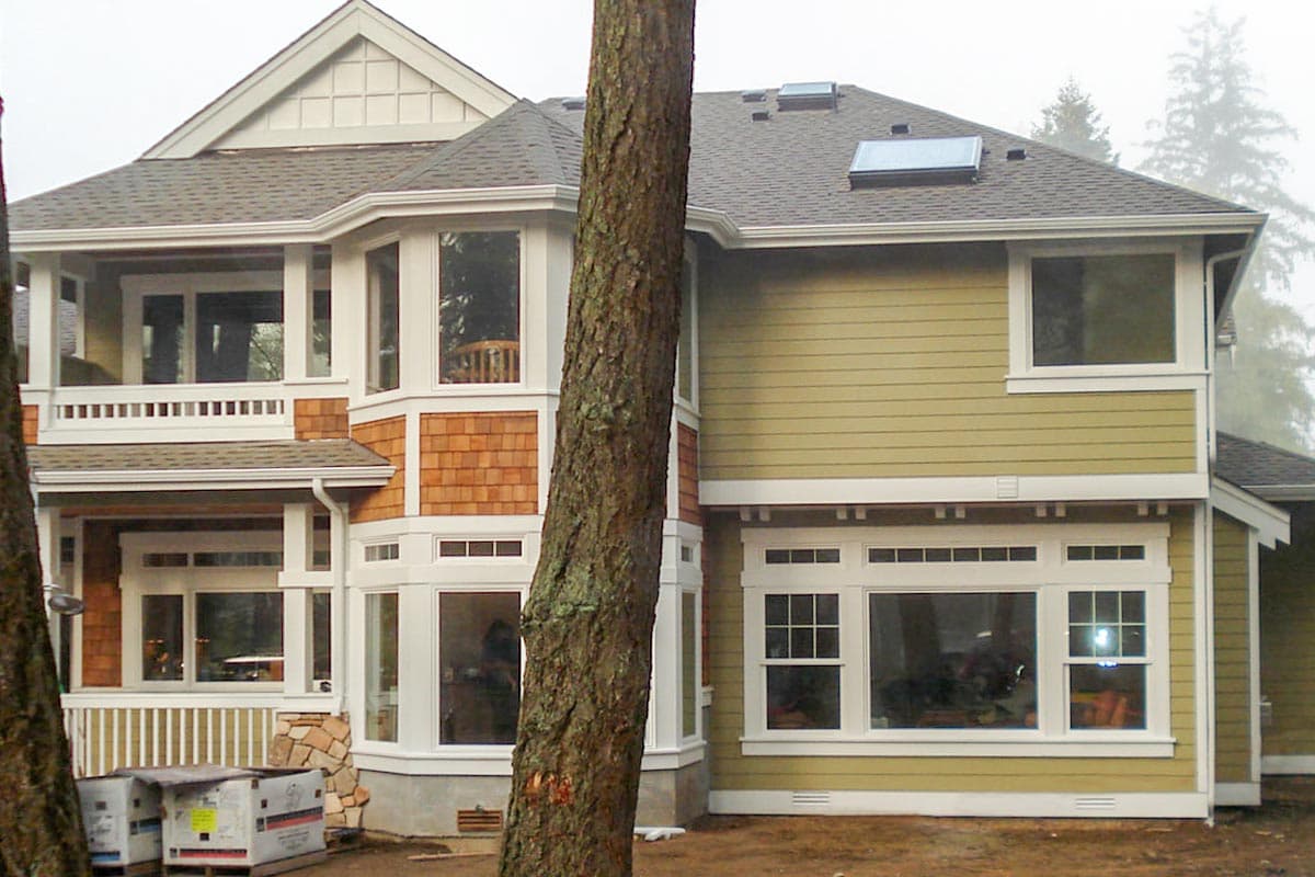 House plan exterior with multi-story design, cedar shake siding, bay windows, and a covered balcony.
