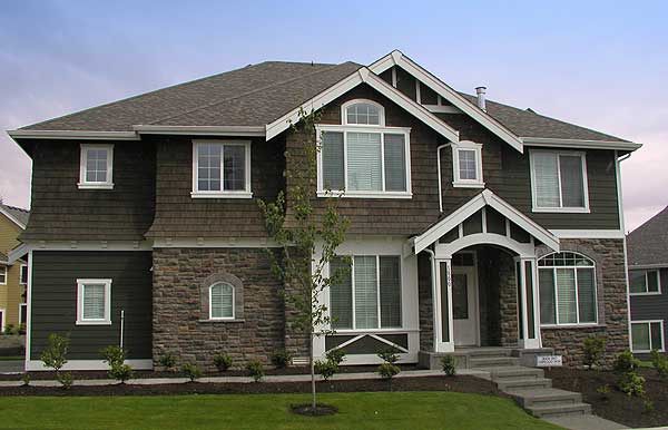 House plan exterior: two-story, dark siding, stone accents, arched entryway, multiple gables, and varied rooflines.