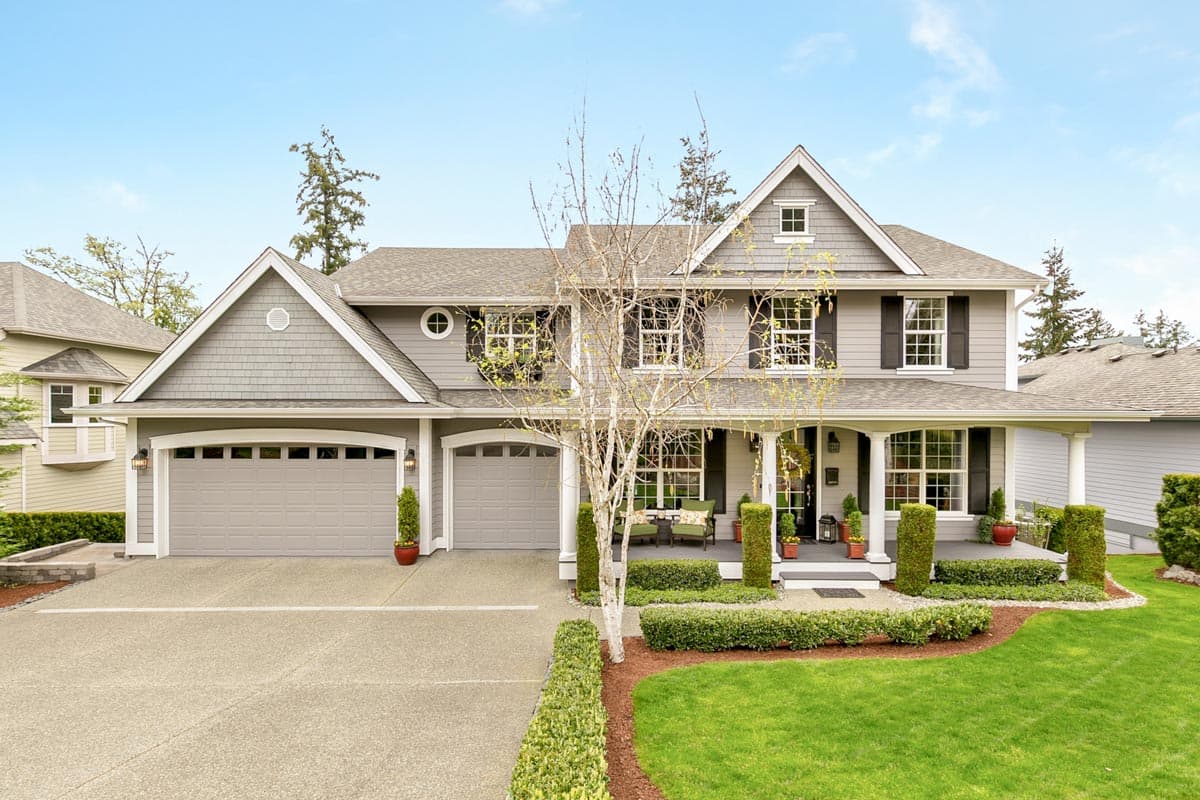 House plan exterior. Two-story home with Craftsman style elements. Features include a front porch, gabled roof, and two-car garage.