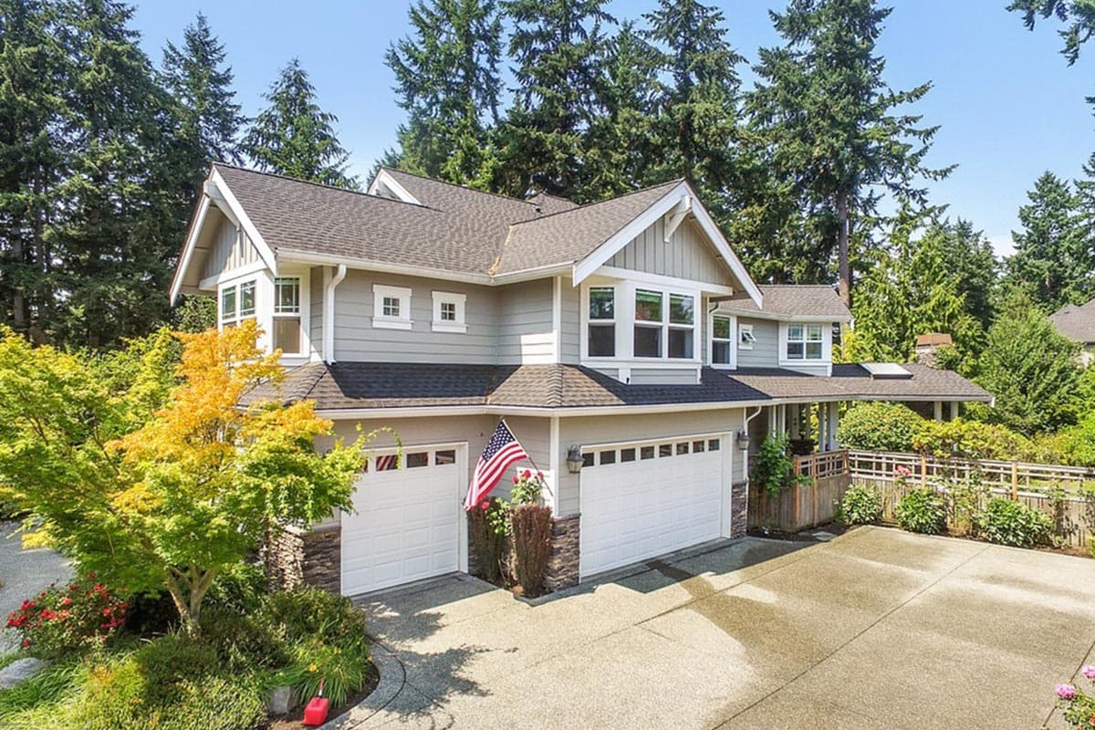 House plan exterior: Two-story home with a gable roof, dormers, stone accents, and a three-car garage.