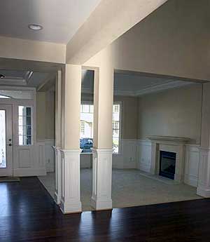 Interior view of a house plan showing a great room with a fireplace and wainscoting, opening to an entryway.