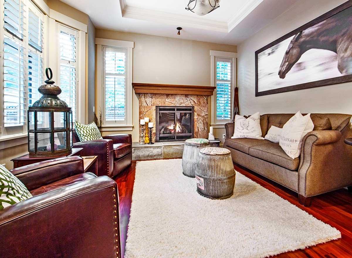Great room interior with stone fireplace, leather armchairs, brown sofa, and tray ceiling.