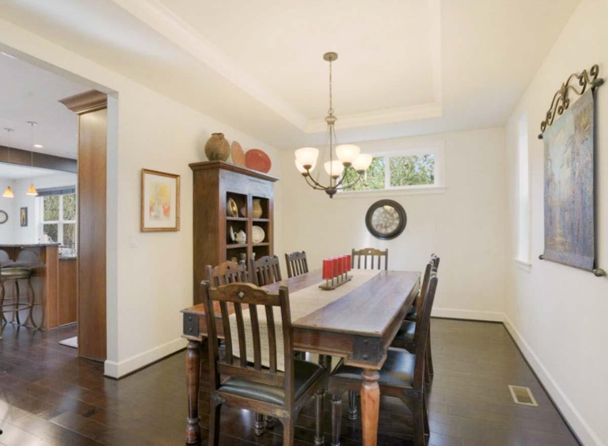 Dining room with dark wood table and chairs, hutch, chandelier, and a wide window.