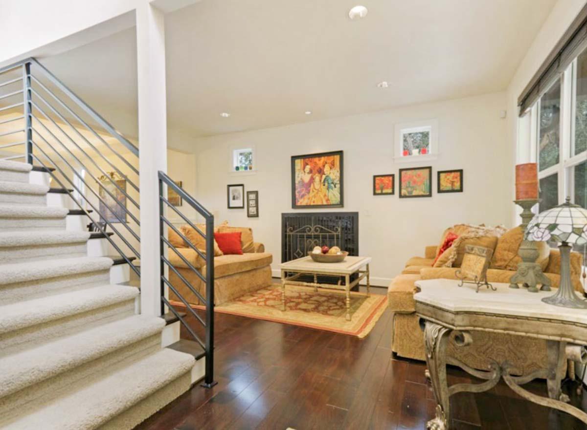 Living room with carpeted stairs, fireplace, and seating area with dark wood floors.