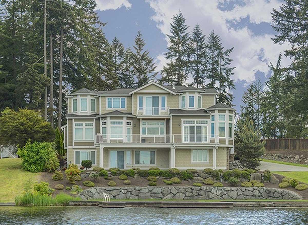 Multi-story house plan exterior with multiple bay windows, balconies, and a covered lower level.