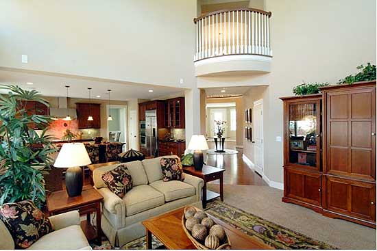Great room with vaulted ceiling, open to kitchen. Features a curved second-floor balcony overlooking the space.