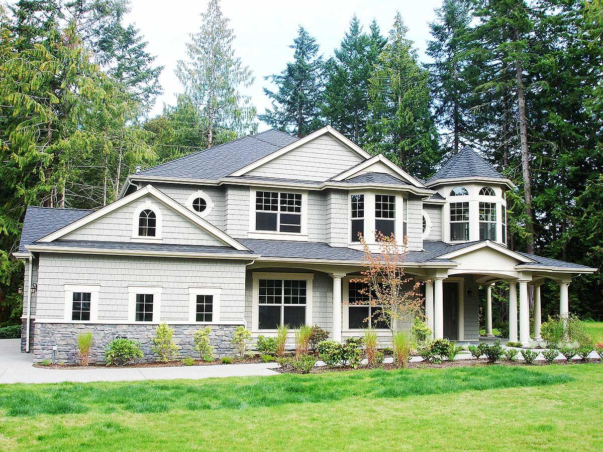 House plan exterior: Two-story home with arched dormers, bay windows, and a rounded turret entrance.