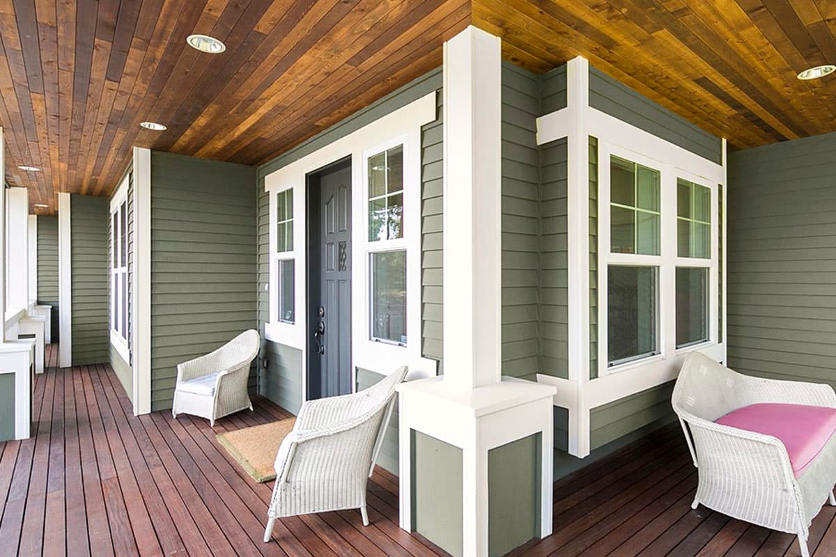 House plan exterior with a covered porch, clapboard siding, wood plank ceiling, and white-trimmed windows.
