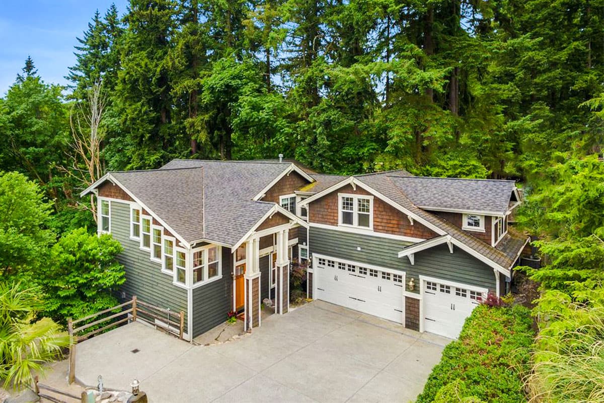 House plan exterior. Craftsman style, two-story home with gables, multiple dormers, and an attached garage. Features an entry porch and wood accents.