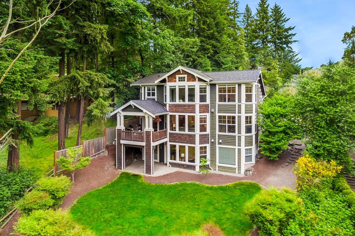 House plan exterior: multi-story home with covered balcony, multiple gables, and varied window arrangements.