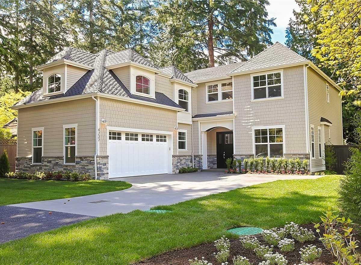 House plan exterior. Two-story home with Craftsman style elements. Features include dormers, a front-entry garage, and gabled rooflines.
