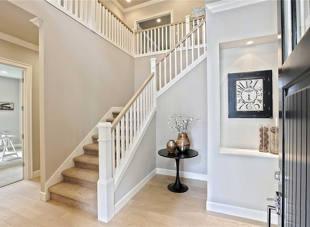 Interior view of a multi-level staircase with white balusters, wood handrails, and carpeted treads.