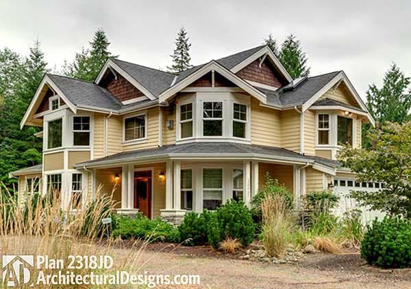 House plan exterior: Two-story home with wraparound porch, bay windows, multiple gables, and wood shingle accents.