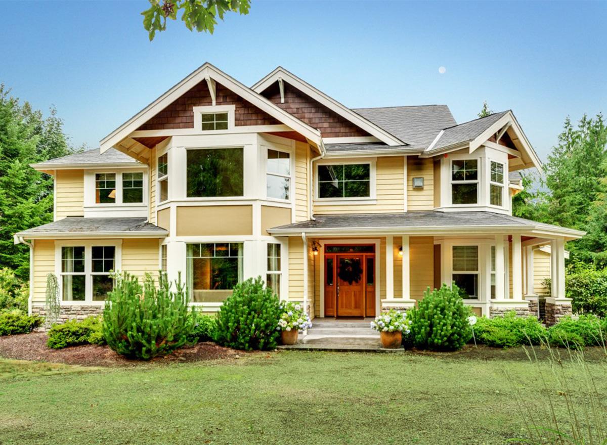 Two-story house plan exterior with gables, bay windows, covered porch, and double-door entry.