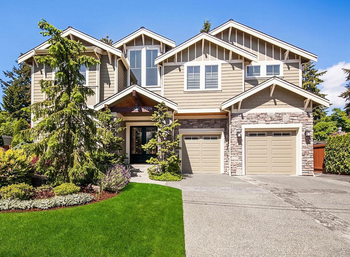 House plan exterior, two stories, siding and stone facade, covered entryway, and two-car garage with gabled roofs.