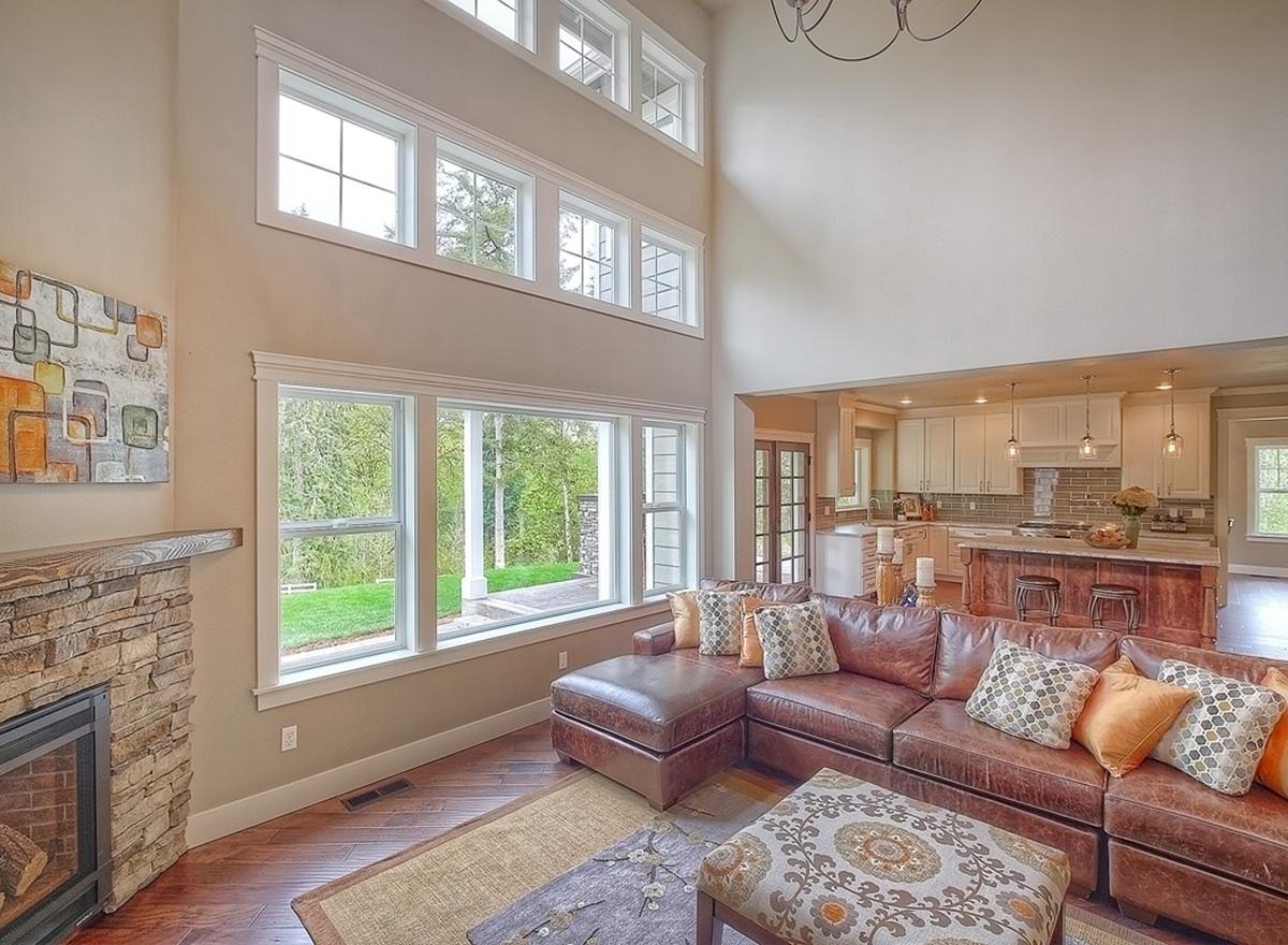 Interior rendering: great room with stone fireplace, vaulted ceiling, and open-concept kitchen with island.