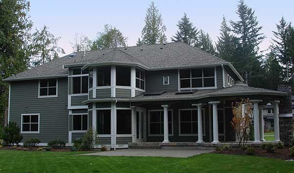 House plan exterior: two-story home with a covered porch, numerous windows, and a bayed sunroom.