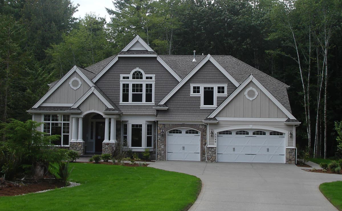 Craftsman style house plan exterior with a two-car garage, arched dormer, stone accents, and a covered entry.