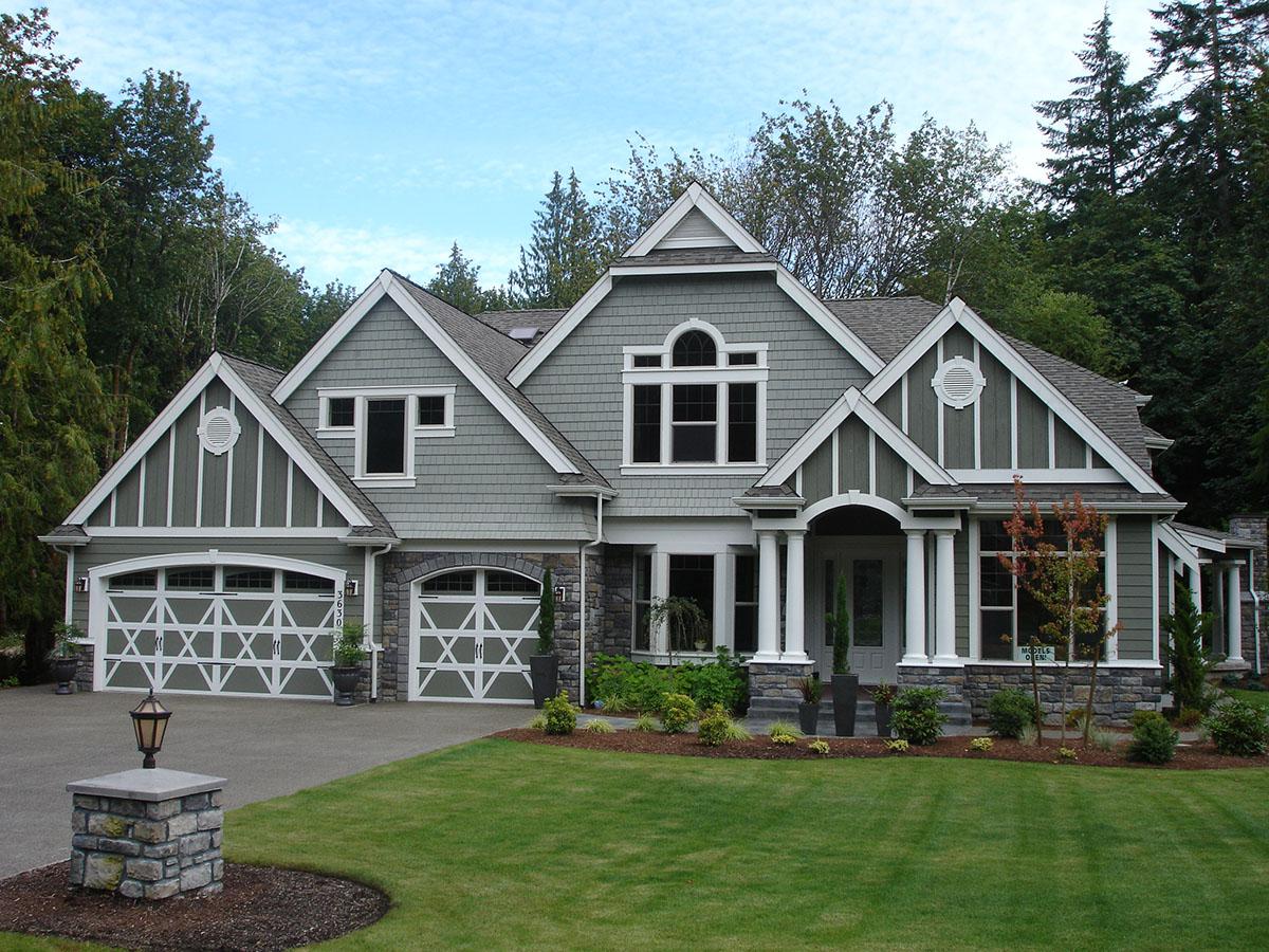 House plan exterior of a two-story home with a multi-gabled roof, stone accents, decorative garage doors, and a covered entryway with columns.