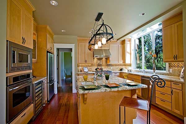 Kitchen with island, stainless steel appliances, light wood cabinetry, granite countertops, and large picture window.