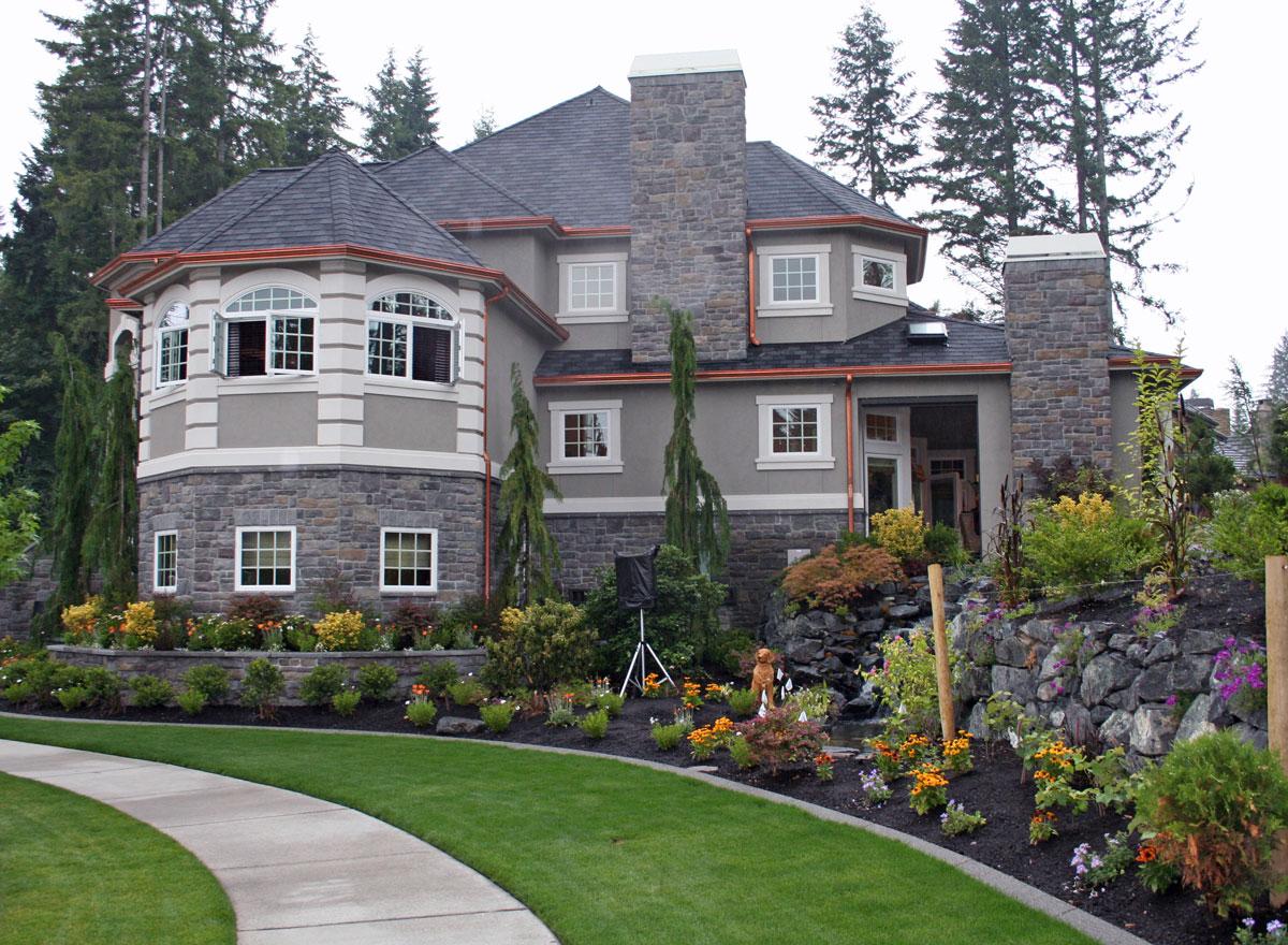 House plan exterior showing a multi-story home with stone facade, turreted bay windows, multiple gables, and stone chimneys.