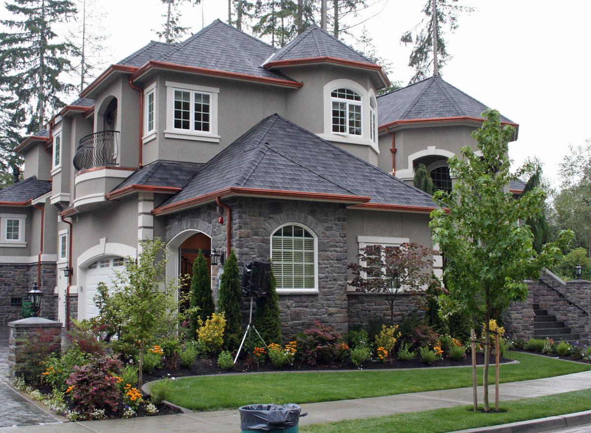 House plan exterior featuring a multi-story design with stone accents, arched windows, a prominent round turret, and a Juliet balcony.