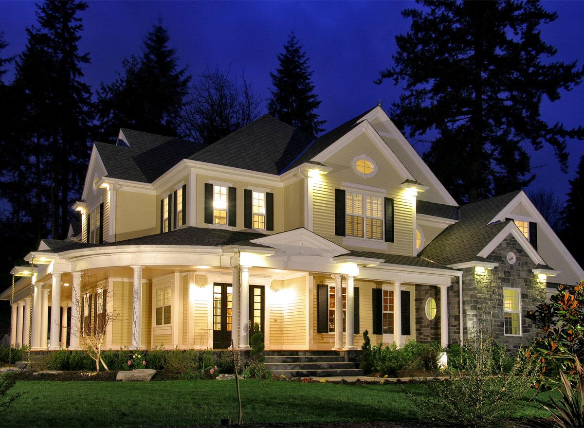 House plan exterior: two-story house with a curved porch, gables, dormers, and stone accents.