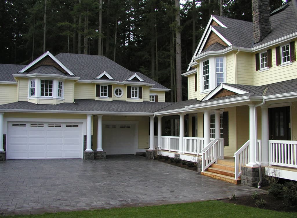 Two-story house plan exterior with a wraparound porch, multiple gables, bay windows, and a side-entry garage.