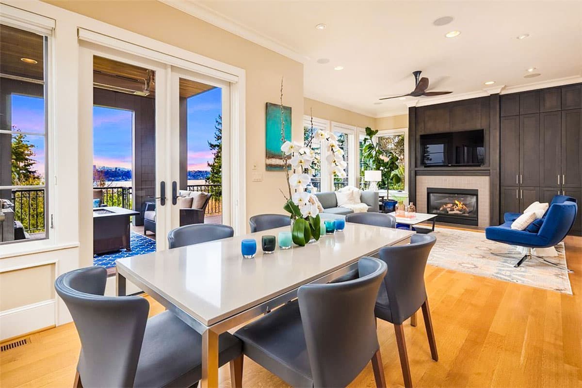Interior rendering of open-concept living and dining area with fireplace, built-in cabinetry, and deck access.